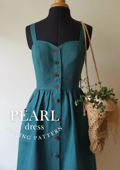 a green dress with buttons on the front and side, hanging from a mannequin