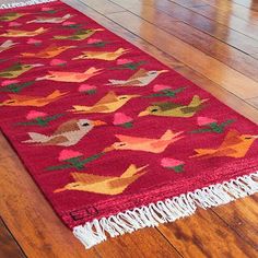 a red rug with birds on it in the middle of a wood flooring area