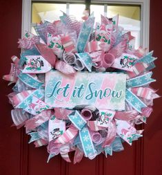 a pink and blue wreath with the words let it snow on it in front of a red door