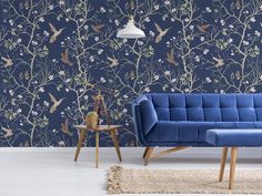 a blue couch sitting in front of a wall with birds on it