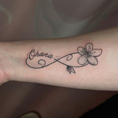 a woman's arm with a tattoo that reads, ohana and has flowers on it