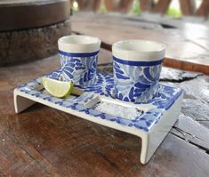 two blue and white cups on a tray with a slice of lime next to them