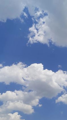 an airplane is flying in the sky with white clouds above it and blue skies below