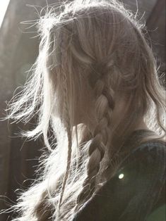 a woman with long hair and braids standing in front of an old brick building