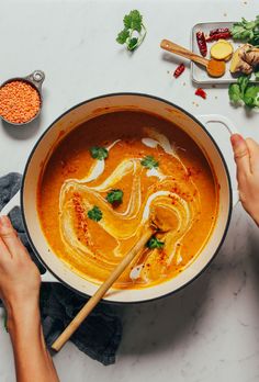 two hands holding chopsticks over a bowl of soup on a white counter top