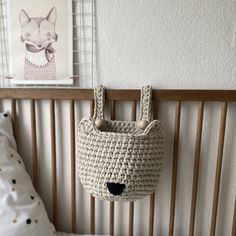 a crocheted purse hanging on the wall next to a baby's bed