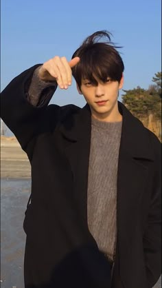 a young man in a black jacket is posing for the camera with his hand on his head