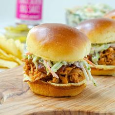 two pulled pork sandwiches with cole slaw on a cutting board