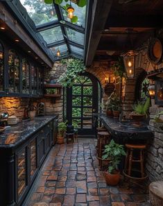 an outdoor kitchen with stone walls and flooring is lit up by lanterns hanging from the ceiling