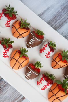 chocolate covered strawberries in the shape of footballs on a white platter with strawberries