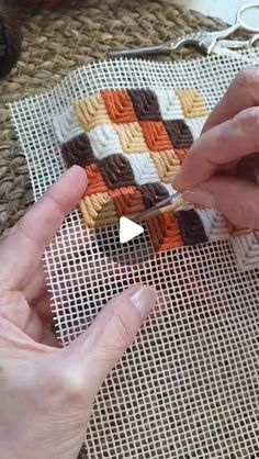 two hands are working on an orange and white piece of fabric that has been stitched together