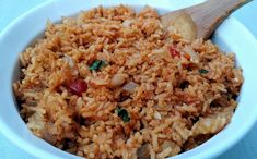 a close up of a bowl of rice with a wooden spoon in the bowl next to it