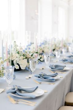 a long table is set with blue and white plates, silverware, and flowers