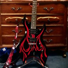 a black and red electric guitar sitting on top of a table next to a dresser