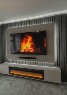 a living room with a large television mounted on the wall and a fire in the fireplace