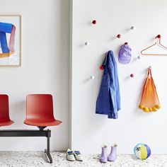 two red chairs sitting next to each other in front of a wall mounted coat rack