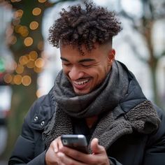 a young man smiles while looking at his cell phone