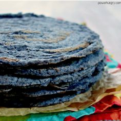 a stack of pancakes sitting on top of a colorful cloth covered tablecloth with torn edges