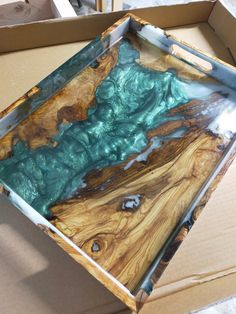 a wooden tray sitting on top of a cardboard box filled with blue and green paint