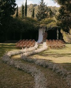 an outdoor ceremony setup with chairs and flowers on the grass, surrounded by trees in the background