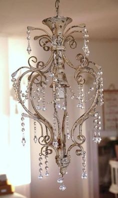 a crystal chandelier hanging from the ceiling in a room with white walls and windows