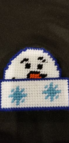 a white and blue cross stitched penguin on a black background