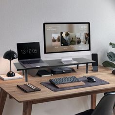 a desk with a monitor, keyboard and mouse on it in front of a plant