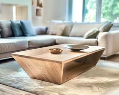 a wooden table sitting on top of a living room floor next to a white couch