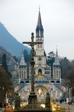 a statue in front of a large building with a cross on it's base