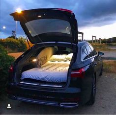 the back end of a black car with its trunk open and it's bed in the trunk