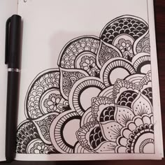 an open notebook with black and white doodle designs on it next to a pen