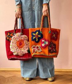 the woman is holding two bags with flowers on them, both in red and orange