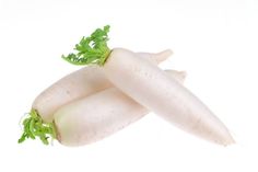 three white radishes with green tops on a white background, one is cut in half