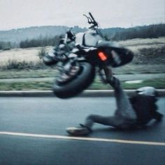 a man falling off his motorcycle on the road