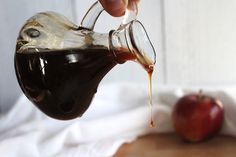 someone pouring caramel syrup into an apple