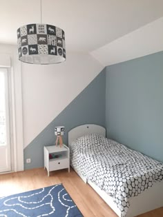 a bedroom with blue and white walls, wooden flooring and a bed in the corner