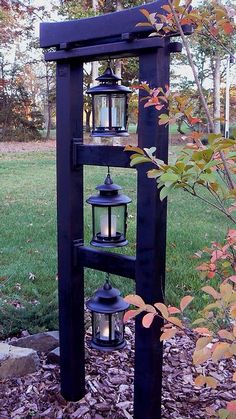 an outdoor shelf with two lanterns on it in the middle of some leaves and grass