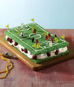 a cake that is on top of a wooden table with a soccer field in the middle