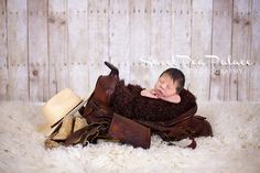 a baby sleeping on top of a pile of brown leather boots and hats in front of a wooden wall