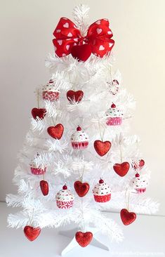 a white christmas tree decorated with red and white cupcakes, hearts and bows