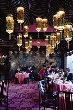 a restaurant with chandeliers hanging from the ceiling and people sitting at tables eating