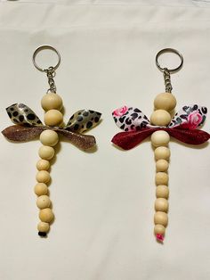 two key chains with wooden beads attached to them, one is shaped like a dragon and the other has a leopard print bow