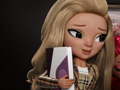 a close up of a doll with blonde hair and big eyes holding a book in her hand