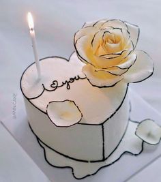 a white cake with a candle in the shape of a heart and a rose on top