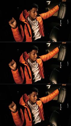 a man in an orange jacket is sitting on a black chair with his arms stretched out