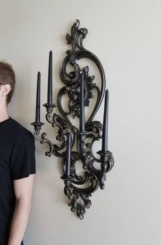 a young man standing next to a wall mounted candle holder