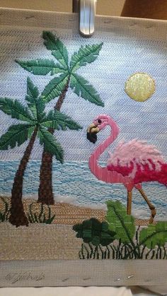 a pink flamingo on the beach with palm trees