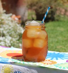 a mason jar filled with iced tea sitting on top of a colorful cloth covered table