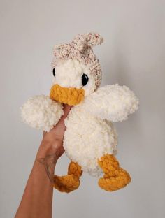 a hand holding a white and yellow stuffed duck