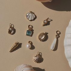 there are many different types of jewelry on the table next to a shell and seashell